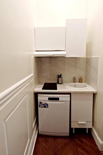 une petite cuisine avec un évier et une cuisinière dans l'établissement L'Atrium Foch, à Paris