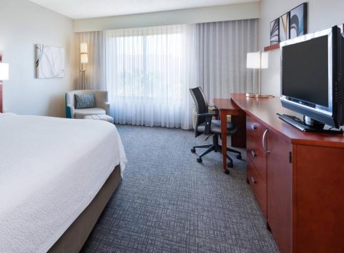 a hotel room with a bed and a desk with a television at Courtyard Harlingen in Harlingen