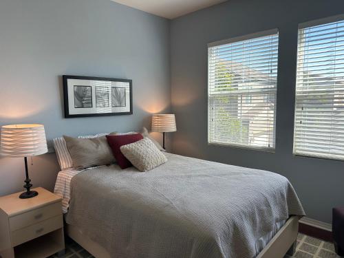 a bedroom with a bed with two lamps and two windows at Strawberry Fields Forever Oxnard Beauty in Oxnard