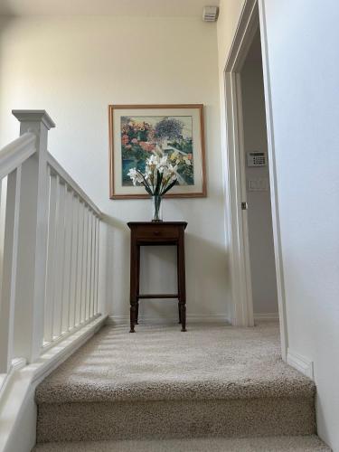 a stairway with a vase of flowers on a table at Strawberry Fields Forever Oxnard Beauty in Oxnard