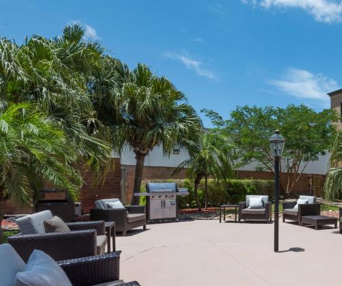 a patio with chairs and a grill and palm trees at Courtyard Harlingen in Harlingen