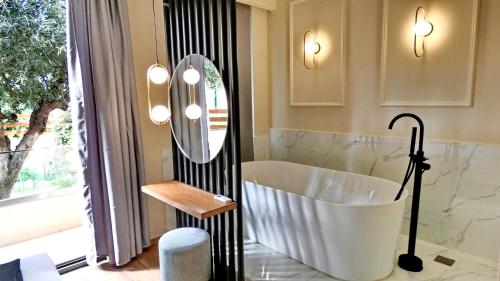a bathroom with a tub and a large mirror at GoldenRoyalSuites in Stalos