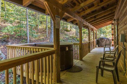 a porch of a cabin with chairs and a grill at Big Boulder Hot Tub Private Hiking in Rogers