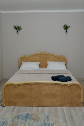 a bed with a wooden headboard and two plants on the wall at Махаббат in Petropavlovsk