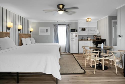 a bedroom with a large white bed and a kitchen at Seabirds Motel At Kure Beach in Kure Beach