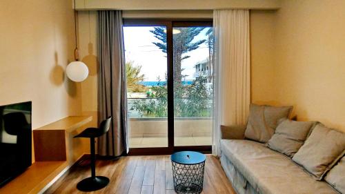 a living room with a couch and a large window at GoldenRoyalSuites in Stalos