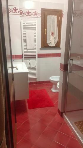 a bathroom with a toilet and a red rug at Il Porticato in Pisa