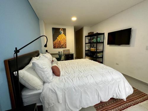 a man laying in a bed with white sheets and pillows at Apartamento Entero 101 in Pereira
