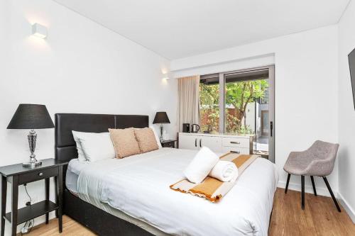 a bedroom with a bed and a chair and a window at Nest on Newcastle - T1 in Perth