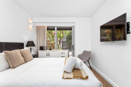 a white bedroom with a large bed and a window at Nest on Newcastle - T1 in Perth