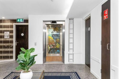 a hallway with a door and a potted plant at Nest on Newcastle - T1 in Perth