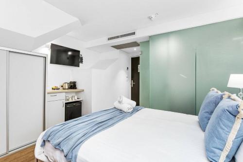 a bedroom with a white bed and a kitchen at Nest on Newcastle - T3 in Perth