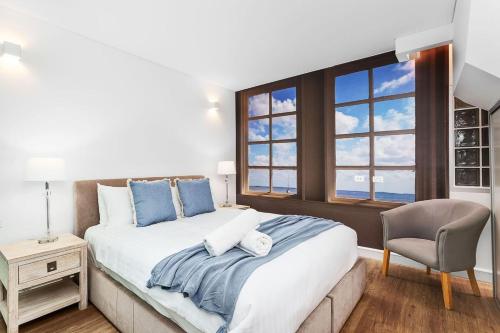 a bedroom with a large bed with a chair and a window at Nest on Newcastle - T3 in Perth
