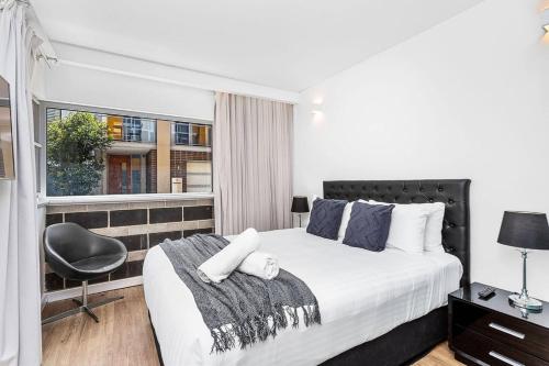 a bedroom with a bed and a chair and a window at Nest on Newcastle - T2 in Perth