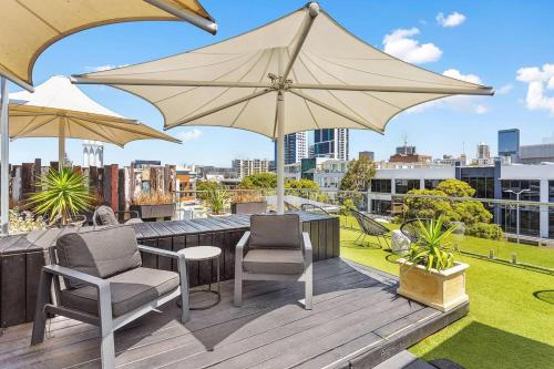 a patio with two chairs and an umbrella on a roof at Nest on Newcastle - T2 in Perth
