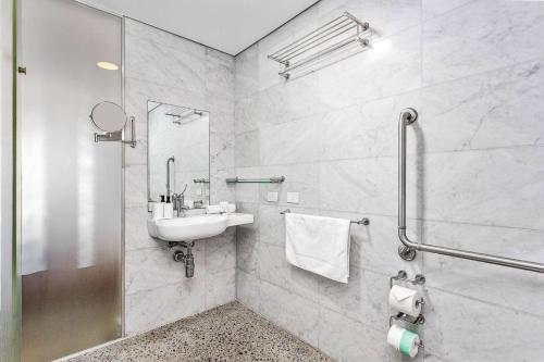 a white bathroom with a sink and a shower at Nest on Newcastle - S4 in Perth