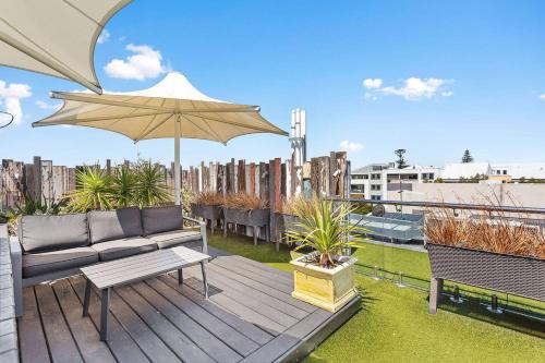 a wooden deck with a couch and an umbrella at Nest on Newcastle - N5 in Perth