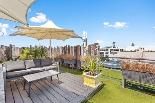 a wooden deck with a couch and an umbrella at Nest on Newcastle - E4 in Perth