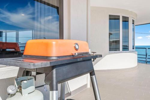 an orange grill on a table with a balcony at Endless Summer - The Reefs in Perth