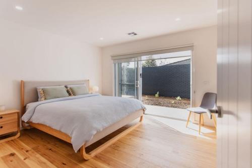 a white bedroom with a bed and a window at Olive Grove - stroll to the beach! in Ocean Grove