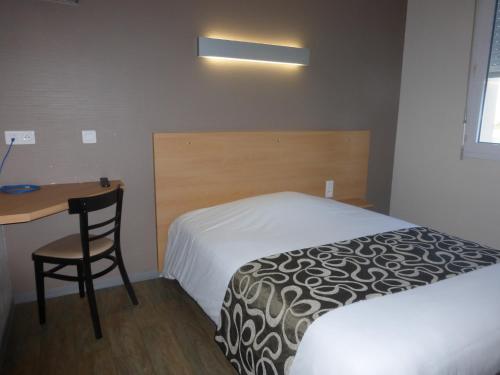 a hotel room with a bed and a desk and a table at La Godinière in Cholet