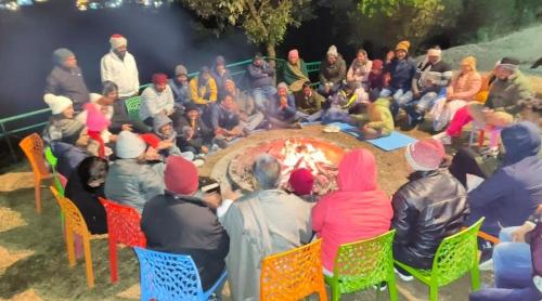 a group of people sitting around a fire at The Himalaya Retreat Resort, Experience Nature in the Lap of Himalayas in Mussoorie