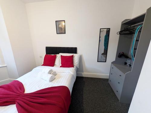 a bedroom with a large bed with red pillows at Comfortable Stay - NG7 in Nottingham