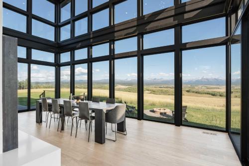 a dining room with a table and chairs and large windows at Mtn Views and Private Hot Tub Luxe Tetonia Retreat in Tetonia