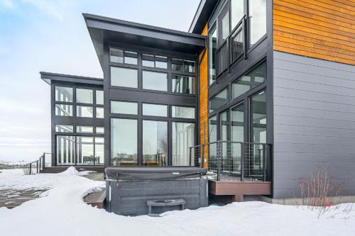 a building with glass windows and a grill in the snow at Mtn Views and Private Hot Tub Luxe Tetonia Retreat in Tetonia