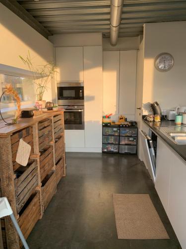 a large kitchen with white cabinets and a counter at Woning gelegen in rustige bosrijke omgeving in Wingene