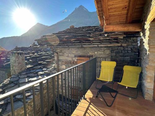 two yellow chairs on a balcony with a mountain at Les Greppes in Bonneval-sur-Arc