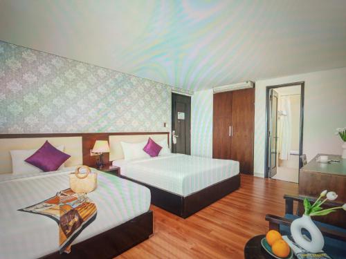 a hotel room with two beds and a table at Agena Hotel City Center in Da Nang