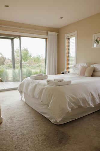 a large white bed in a bedroom with a large window at Tuki Views House with pool and spa in Havelock North