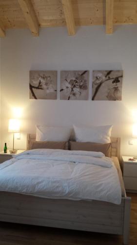 a bedroom with a white bed and two paintings on the wall at Ferienwohnung Vitalis in Bad Bayersoien