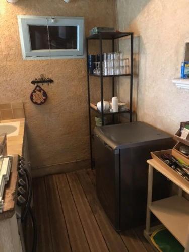 Il comprend une cuisine équipée d'un réfrigérateur noir et d'une étagère. dans l'établissement Maison de campagne en plein village, à Fontvieille