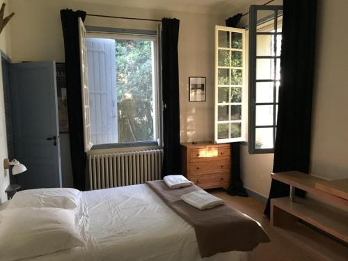 une chambre avec un grand lit et une fenêtre dans l'établissement Maison de campagne en plein village, à Fontvieille