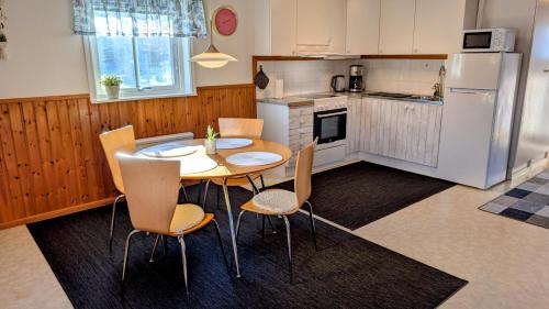 a kitchen with a table and chairs and a refrigerator at Liten uggla in Dalskog