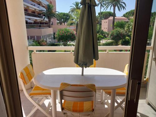 une table et des chaises avec un parasol sur un balcon dans l'établissement 2 piéces terrasse clilm à 400 M de la Mer, au Golfe-Juan
