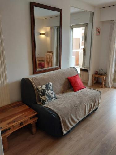 - un canapé dans le salon avec un miroir dans l'établissement 2 piéces terrasse clilm à 400 M de la Mer, au Golfe-Juan