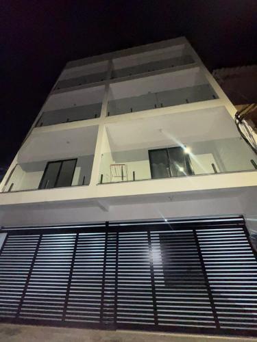 a tall white building with a fence in front of it at Flats super bem localizado! in Arraial do Cabo