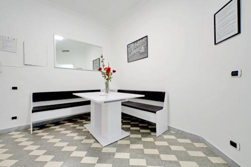 a white room with a vase of flowers on a table at Stella Polare Sensorial Home in Lido di Ostia