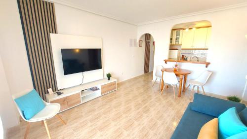 a living room with a blue couch and a tv at Arenales Sea View Apartment in Arenales del Sol
