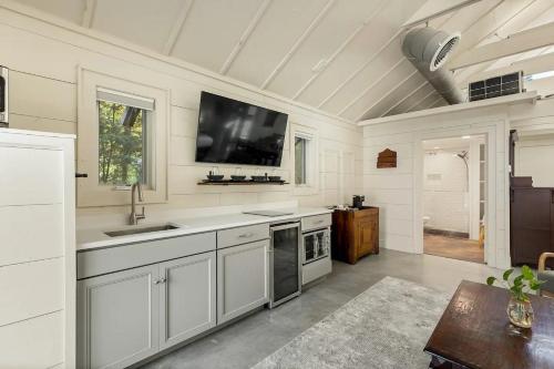 a kitchen with white cabinets and a flat screen tv at The Wells Cashiers in Cashiers