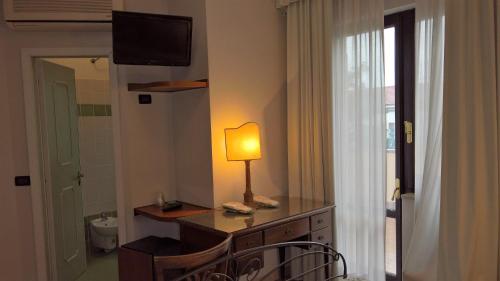um quarto com um candeeiro numa cómoda com uma janela em Hotel La Rotonda em Cepagatti