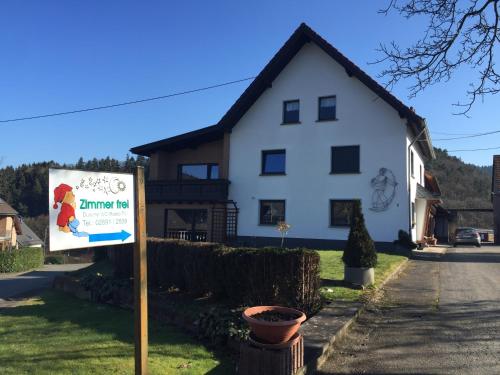 ein weißes Haus mit einem Schild davor in der Unterkunft Privatzimmer Hoffmann in Kaltenborn