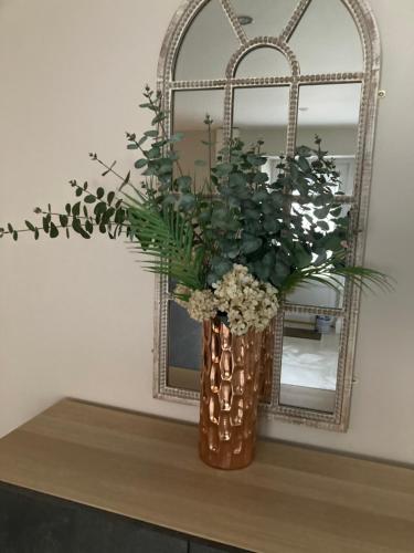 a vase with flowers on a table in front of a mirror at Dalys Back House in Béal Átha Póirin