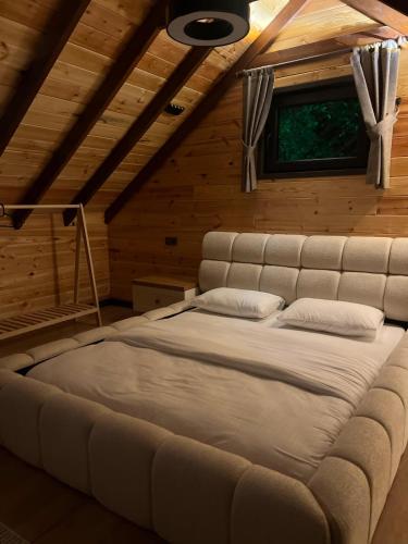a large bed in a wooden room with a window at Bell Garden Maşukiye in Kocaeli