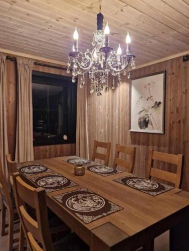 a dining room table with chairs and a chandelier at Trysil turistesenter hytte in Trysil