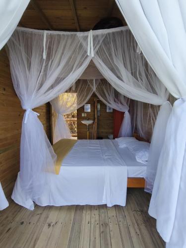 a bedroom with a bed with white sheets and curtains at Casa Acuarimantima in Tintipan Island
