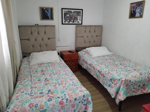 a bedroom with two beds and a night stand at Hostal Estadio Nacional in Santiago